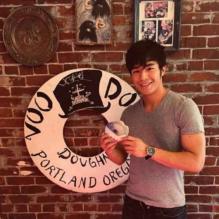 Beck Chen smiling while holding a doughnut in Portland, Oregon
